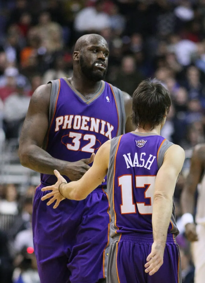 Shaquille O'Neal (Suns #32) and teammate Steve Nash (#13, back to camera) slap hands on court.